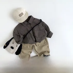Flat lay of kids dark grey cargo shirt, khaki pants and puppy shaped crossbody bag