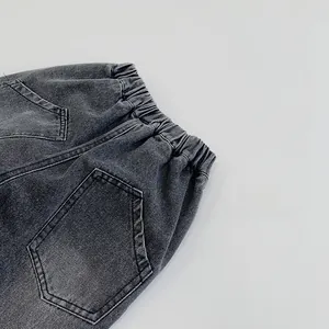Detail view of elastic waistband and stitched back pocket on dark gray kids denim jeans