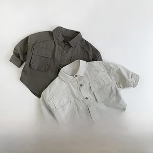 Detailed view of two children's cargo shirts in olive and beige with front flap pockets