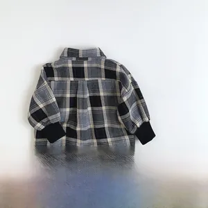 Détail de chemise à carreaux pour enfant montrant le flanelle bleu et gris et les poignets