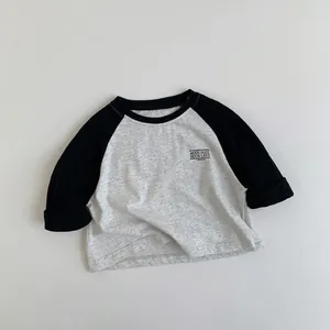 Detalle de camiseta infantil de manga larga raglán en algodón gris y negro con estampado
