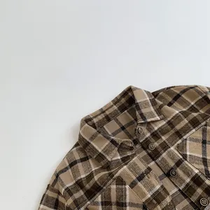 Detailed view of brown plaid flannel fabric with dark buttons on a long sleeve shirt