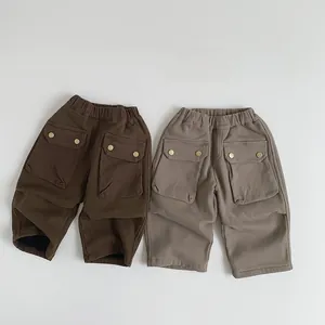 Detail of children cargo pants in brown and khaki with elastic waist and large pockets