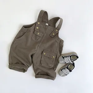 Flachbild-Detail der braunen Baumwoll-Kinder-Latzhose und gestreiften Canvas-Sneakers