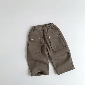 Detail of dark brown kids cargo pants featuring elastic waist and large flap pockets