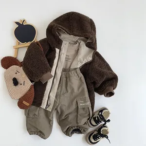 Detailed flat lay of a children's brown fleece hooded jacket with warm winter accessories