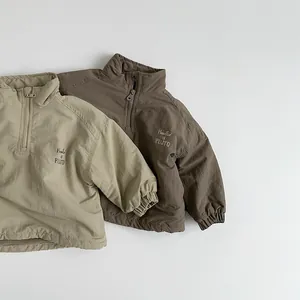 Detail of half-zip kids pullover jackets in khaki and brown with chest print