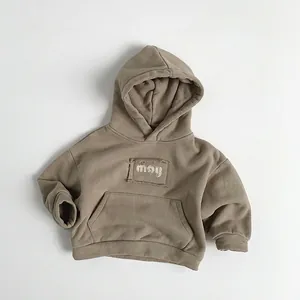 Detail of kids hooded fleece sweatshirt in brown with chest patch and front pocket