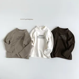 Détail de trois t-shirts manches longues enfant en kaki, crème et marron avec motif arc-en-ciel