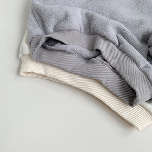 Detail shot of soft fleece fabric and high-elastic ribbed hem on grey and beige kids sweaters