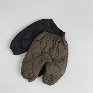Detail of children's quilted pants with diamond patterns and elastic waist in black and coffee