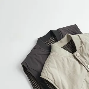 Detail of reversible quilted vest for kids with snap buttons and plaid pattern lining