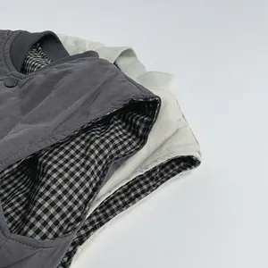 Detail view of double-sided kids vest with gingham lining and matte snap button