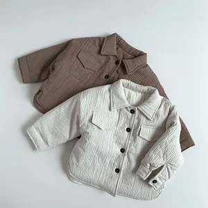 Flat lay of quilted cotton shirts for children in brown and cream with vertical stitching