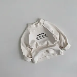 Détail du sweat-shirt crème pour enfants avec col rond côtelé et typographie noire élégante