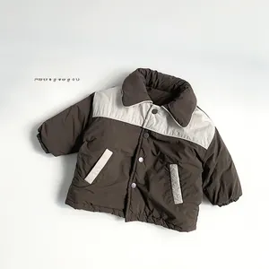 Détail de la veste d'hiver enfant avec boutons-pression et poches contrastées marron et beige