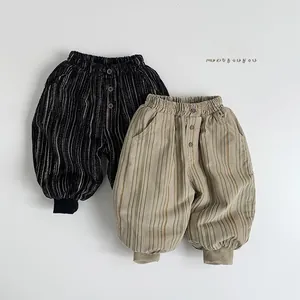 Detail of kids corduroy trousers featuring wooden buttons and elastic high waist