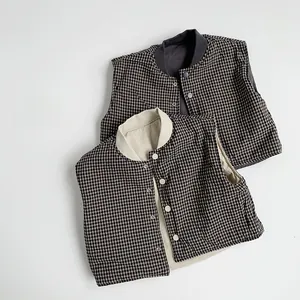 Detail of reversible plaid vests for children featuring snap buttons and stand-up collars