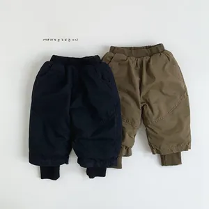 Dettaglio di vita elastica e polsini a costine su pantaloni in cotone blu e verde oliva