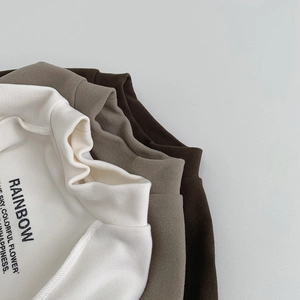 Détail de trois chemises thermiques empilées en blanc, taupe et marron foncé pour hiver