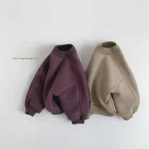 Close-up of oversized fleece sweatshirts for kids in burgundy and beige with ribbed cuffs