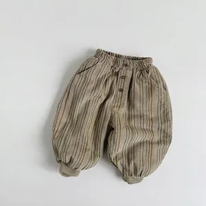 Close-up of corduroy pants with vertical brown and green stripes and vintage buttons