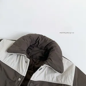Détail d'une veste matelassée pour enfant avec boutons pression et tissu en nylon
