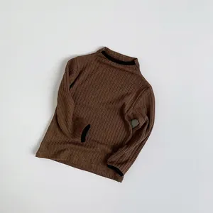 Close-up of brown ribbed knit sweater featuring contrasting black trim at the neck and cuffs