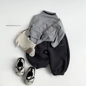 Flat lay of gray ribbed knit sweater and dark thermal joggers with a puppy bag and sneakers