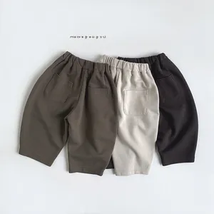 Detailed view of three pairs of children's knit trousers in brown, beige, and black colors
