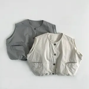 Detailed flat lay of quilted kids vests in dark grey and beige with front pockets