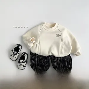 Detailed flat lay of beige crewneck sweatshirt and black striped velvet pants outfit