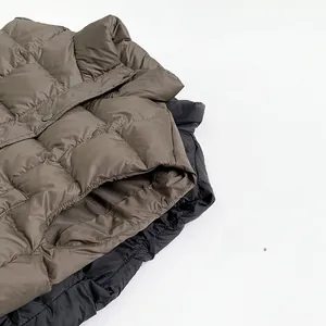 Detail view of quilted puffer vests in olive brown and black with square stitch patterns