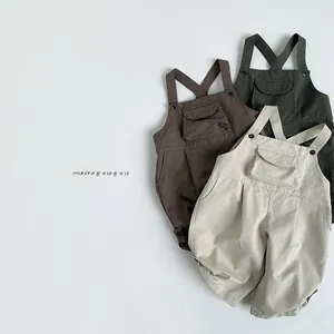Detailed flat lay of three cotton overalls in olive, brown, and beige with front pockets