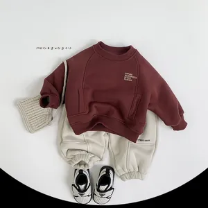 Flat lay of wine red fleece sweatshirt with white joggers and knit crossbody bag for kids