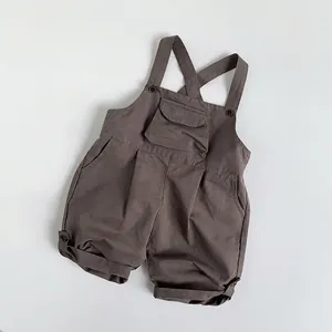 Detail of dark brown cotton kids overalls with functional front pocket and cross straps