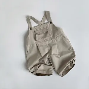 Detail of light beige cotton kid's overalls showing decorative chest pocket and texture