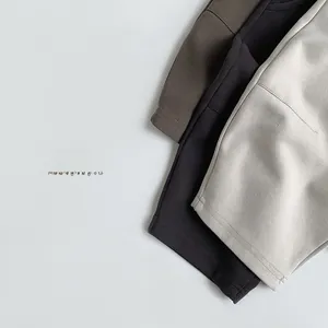 Detailed view of layered thick cotton knitted trousers in beige, dark grey, and brown