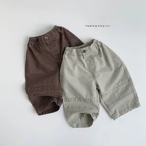 Detail view of elastic waistband and decorative button on kid's cotton cargo pants