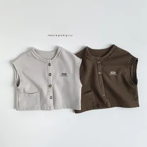 Détail de gilets en coton pour enfants avec bords francs et écusson à slogan en deux coloris