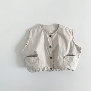 Detail of children's beige vest featuring dark buttons and elastic hem on cotton fabric