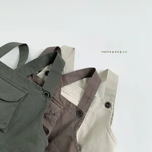 Detail of kids overalls showing utility straps and cargo pockets in earth tones