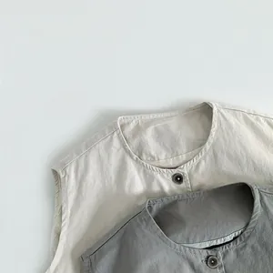 Detail view of cotton linen kids' vests with vintage buttons in cream and charcoal grey