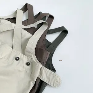 Close-up of kids cotton overalls with adjustable straps and vintage brown buttons