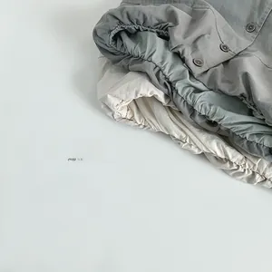 Detail of kids' cotton vests in grey, green, and beige with button and pleated texture