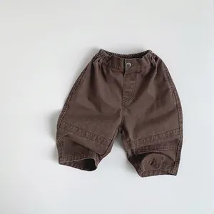Detail view of dark brown kids cotton trousers with elastic waist and stitched seams