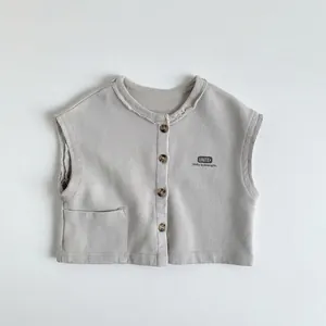 Détail du gilet gris pour enfant montrant boutons marron et texte imprimé UNITE