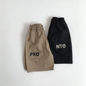 Detail of khaki and black kids cargo shorts with elastic waist and lettered pockets