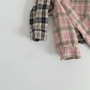 Detail of color-block plaid shirt showing pink and brown fabric texture and white button cuff