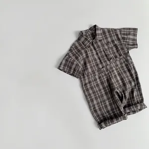 Detail view of plaid baby romper with small pocket and buttons on a grey background